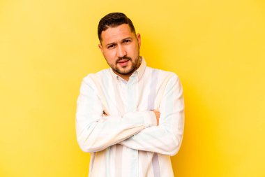 Sarı arka planda kendini güvende hisseden, kararlılıkla kollarını kavuşturan genç İspanyol bir adam..