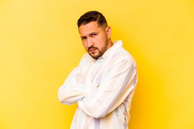 Sarı arka planda izole edilmiş genç bir İspanyol şüpheli, belirsiz, seni muayene ediyor..