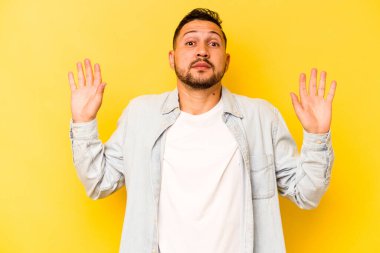 İspanyol genç adam sarı arka planda izole edilmiş. Yakın bir tehlike nedeniyle şoka uğruyor.