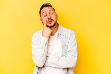 Genç İspanyol adam sarı arka planda izole edilmiş ağlıyor, bir şeyden memnun değil, acı ve kafa karışıklığı konsepti..