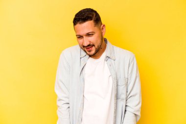 Sarı arka planda izole edilmiş genç İspanyol adam gülüyor ve gözlerini kapıyor, rahatlamış ve mutlu hissediyor..