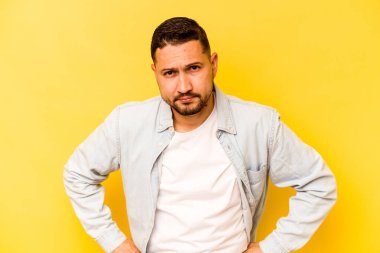 Genç İspanyol adam sarı arka planda izole edilmiş üzgün, ciddi yüzlü, mutsuz ve hoşnutsuz..