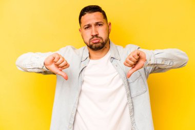 Sarı arka planda izole edilmiş, hoşlanmadığı bir hareket gösteren genç bir İspanyol. Anlaşmazlık konsepti.