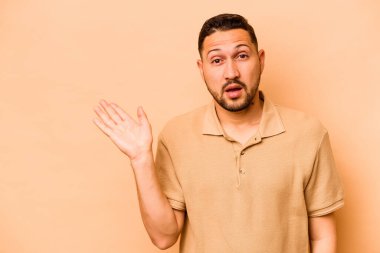 Latin kökenli genç adam bej arka planda izole edilmiş..
