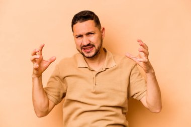 Genç İspanyol adam bej arka planda izole edilmiş öfkeyle bağırıyor..