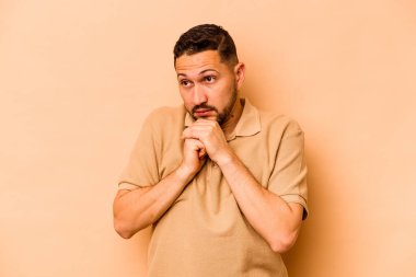 Genç İspanyol adam bej arka planda izole edilmiş korkmuş ve korkmuş..
