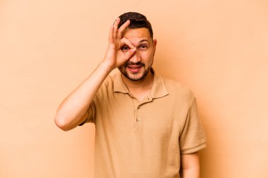 Latin kökenli genç adam bej arka planda izole edilmiş. Heyecanlı..