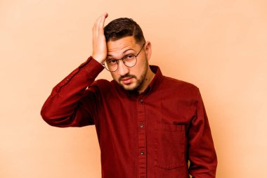 Latin kökenli genç adam bej arka planda izole edilmiş. Çok yorgun ve uykulu. Elini başının üstünde tutuyor..