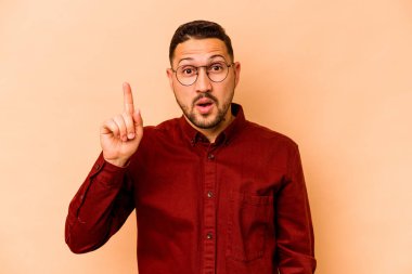 Latin kökenli genç bir adam bej arka planda izole edilmiş. Harika bir fikri var, yaratıcılık kavramı..