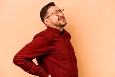 Genç İspanyol adam bej arka planda izole edilmiş sırt ağrısı çekiyor..