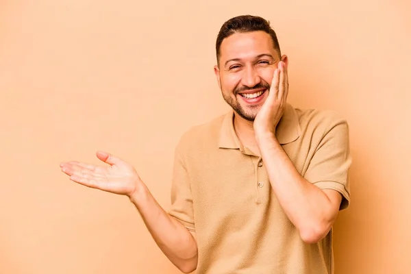 Jonge Latijns Amerikaanse Man Geïsoleerd Beige Achtergrond Houdt Kopieerruimte Een — Stockfoto