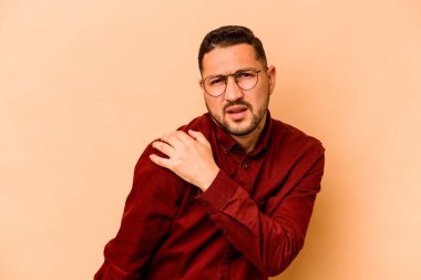 Bej arka planda izole edilmiş genç İspanyol bir adam omuz ağrısı çekiyor..