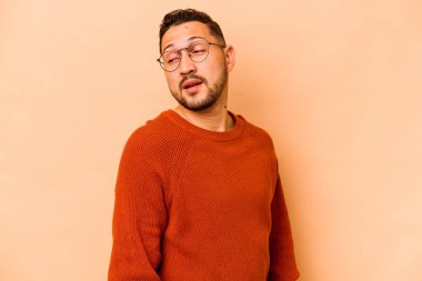 Latin kökenli genç adam bej arka planda izole edilmiş. Gülümsüyor, neşeli ve keyifli görünüyor..