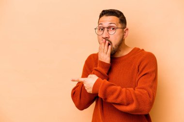 Latin kökenli genç adam bej arka planda izole edilmiş.