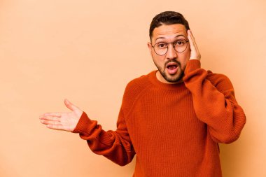 Latin kökenli genç adam bej arka planda izole edilmiş..