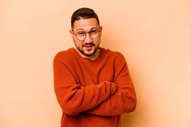 Genç İspanyol adam bej arka planda izole edilmiş mutlu, güler yüzlü ve neşeli.