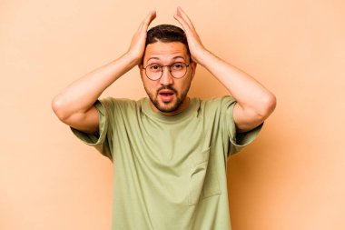 Latin kökenli genç bir adam, bej arka planda izole edilmişti..