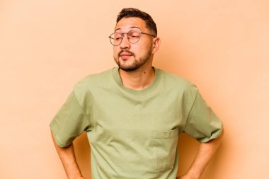 Latin kökenli genç adam bej arka planda izole edilmiş hedeflerine ve amaçlarına ulaşma hayali kuruyor.