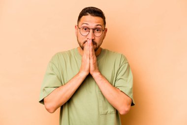 Latin kökenli genç adam bej arka planda izole edildi..