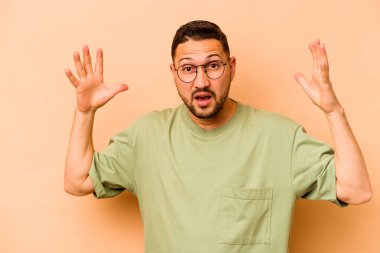 Latin kökenli genç bir adam zaferi ya da başarıyı kutluyor, şaşırmış ve şok olmuş..