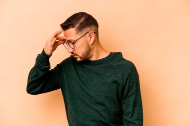 Latin kökenli genç bir adam bej arka planda izole edilmiş, başı ağrıyor, yüzüne dokunuyor..