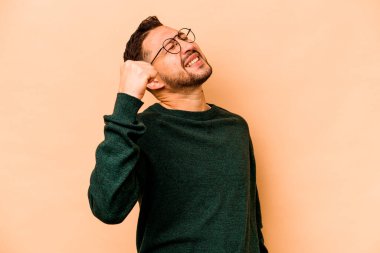 Latin kökenli genç adam bej arka planda izole edilmiş zafer, tutku ve coşkuyu kutluyor, mutlu bir ifade..