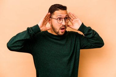 Genç İspanyol adam bej arka planda izole edilmiş bağırıyor, çok heyecanlı, tutkulu, bir şeyden memnun..