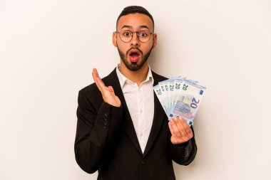 Genç İspanyol iş adamının elinde banknotlar var. Beyaz arka planda izole edilmiş. Şaşırmış ve şok olmuş..