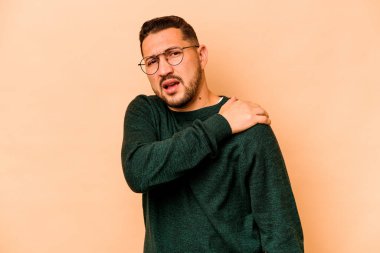 Bej arka planda izole edilmiş genç İspanyol bir adam omuz ağrısı çekiyor..