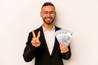 Genç İspanyol iş adamının elinde banknotlar var. Beyaz arka planda iki numarayı parmaklarıyla gösteriyor..