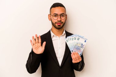 Genç İspanyol işadamının elinde banknotlar var. Beyaz arka planda izole edilmiş. Beş numarayı parmaklarıyla gülümsüyor..