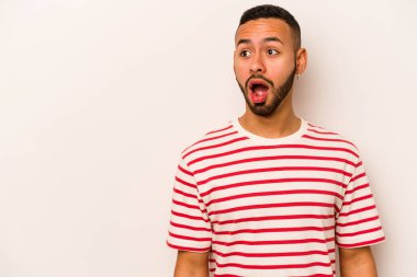Beyaz arka planda izole edilmiş genç İspanyol adam gördüğü bir şey yüzünden şoka uğruyor..