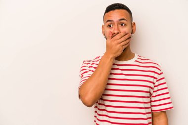 Genç İspanyol bir adam beyaz arka planda izole edilmiş. Düşünceli bir şekilde bir fotokopi odasına bakıyor. Ağzını eliyle kapatıyor..