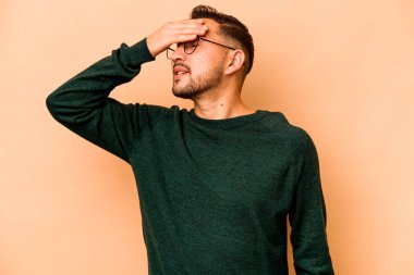 Latin kökenli genç bir adam bej arka planda izole edilmiş, elleriyle gözlerini kapatmış, gülümseyerek bir sürpriz bekliyor..