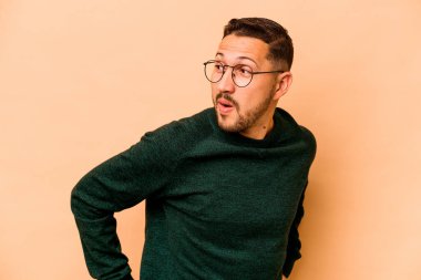 Latin kökenli genç adam bej arka planda izole edilmiş. Gülümsüyor, neşeli ve keyifli görünüyor..