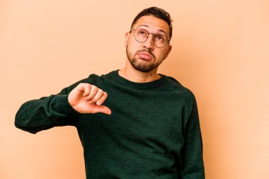 Latin kökenli genç bir adam bej arka planda izole edilmiş, hoşlanmadığı bir jest gösteriyor, kabul etmiyor. Anlaşmazlık konsepti.