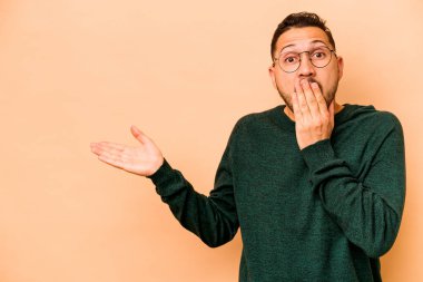 Latin kökenli genç adam bej arka planda izole edilmiş..