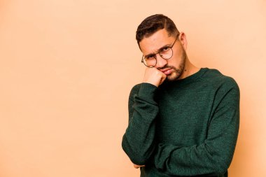 Bej arka planda izole edilmiş, üzgün ve dalgın hisseden ve fotokopi alanına bakan İspanyol genç adam..