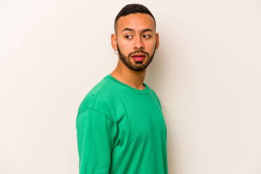 Beyaz arka planda soyutlanmış genç İspanyol adam gülümseyen, neşeli ve keyifli bir kenara bakıyor..