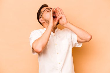 Latin kökenli genç adam bej arka planda izole edilmiş..