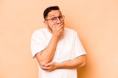 Genç İspanyol adam bej arka planda izole edilmiş korkmuş ve korkmuş..