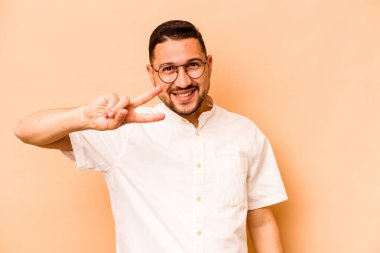 Genç İspanyol adam bej arka planda izole edilmiş dans ediyor ve eğleniyor..