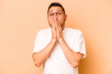Latin kökenli genç adam bej arka planda izole edildi..