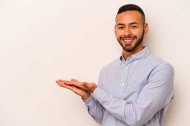 Beyaz arka planda izole edilmiş genç İspanyol bir adam avucunun içinde bir kopyasını tutuyor..