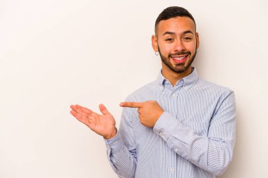 Beyaz arka planda izole edilmiş genç İspanyol bir adam heyecanlı bir şekilde avuç içinin bir kopyasını tutuyor..