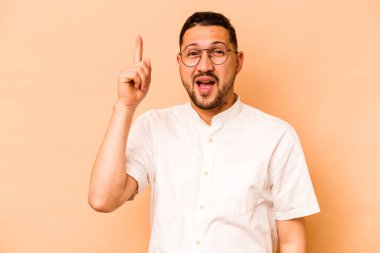 Latin kökenli genç bir adam bej arka planda izole edilmiş. Bir fikri var, ilham verici bir kavram..