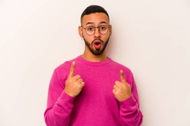 Beyaz arka planda izole edilmiş genç bir İspanyol ağzı açık bir şekilde yukarı işaret ediyor..