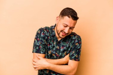 Genç İspanyol adam bej arka planda izole edilmiş gülüyor ve eğleniyor..