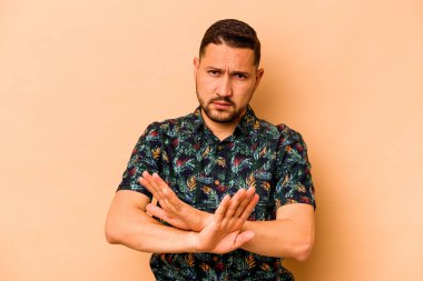 Latin kökenli genç bir adam, bej arka planda izole edilmiş, inkar hareketi yapıyor.