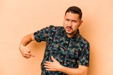 Latin kökenli genç bir adam bej arka planda karaciğer ağrısı ve karın ağrısı çekiyor..